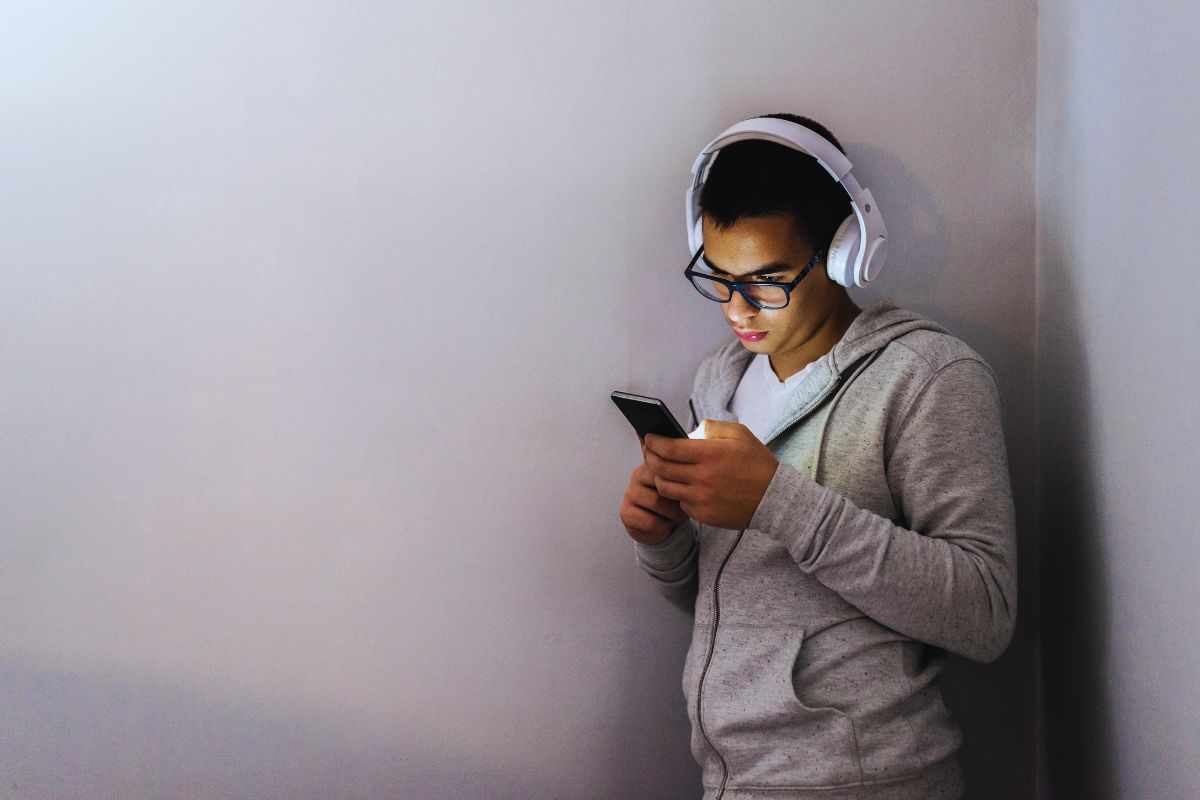 Ragazzo con cuffie che guarda smartphone